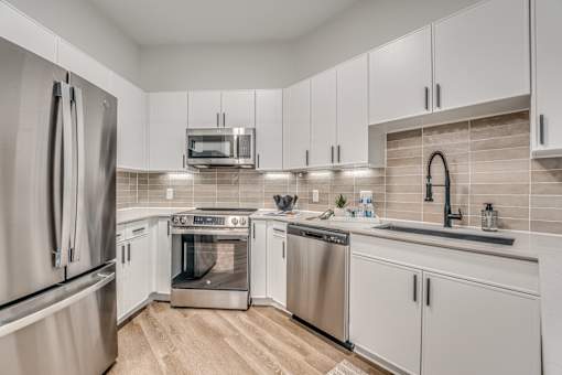 Modern kitchen with white cabinetry and stainless appliances at The Montrose Apartments, Dallas, TX 75204