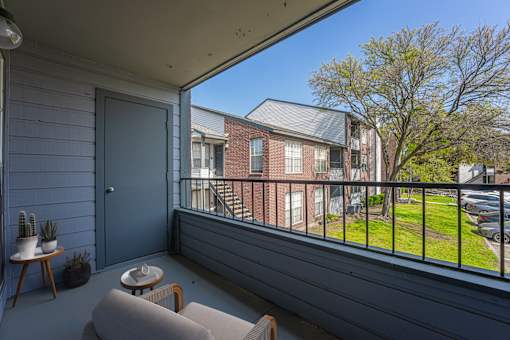A balcony with a grey floor and a blue door.