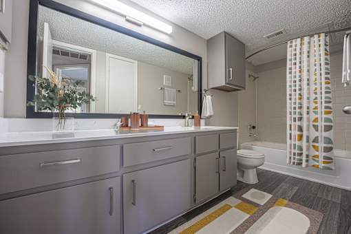 A bathroom with a sink, mirror, toilet, and shower.