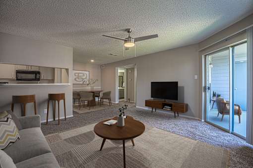 A living room with a grey couch, a wooden coffee table, and a television.