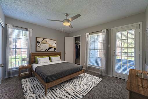 A bedroom with a bed, dresser, and sliding glass doors.