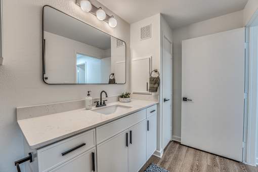 Bathroom vanity with modern fixtures and large mirror at The Barton Apartments, Dallas, TX 75206
