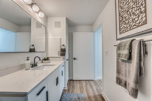 Modern bathroom with white vanity and wood flooring at The Barton Apartments, Dallas, TX