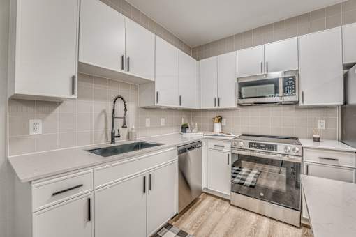 Modern kitchen with white cabinets and stainless appliances at The Barton Apartments, Dallas