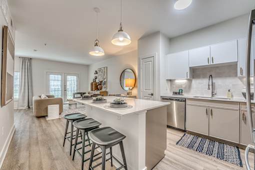 A kitchen with a white island and bar stools.