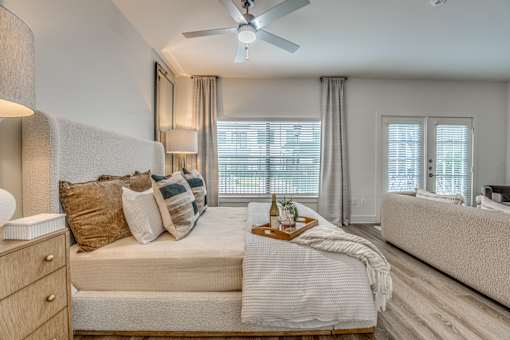 A well-lit bedroom with a large bed and a ceiling fan.