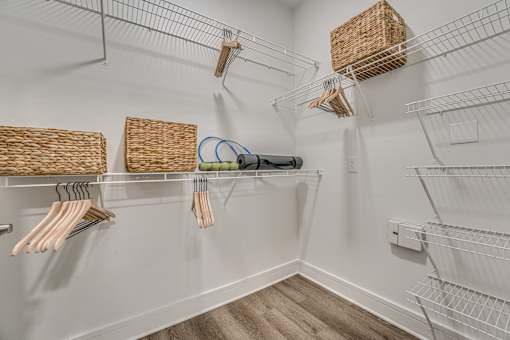 A white closet with clothes hangers and baskets.