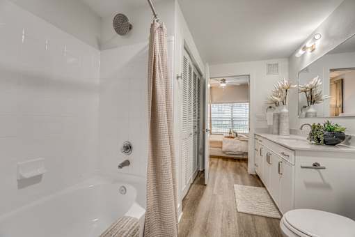 A bathroom with a white tub and a beige shower curtain.
