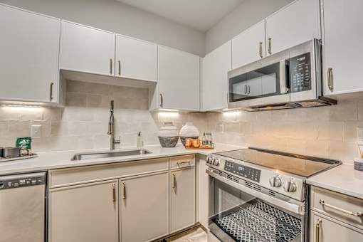 A modern kitchen with white cabinets and stainless steel appliances.
