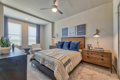 A bedroom with a bed, nightstand, and a plant.