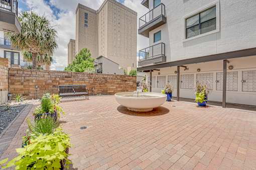 Courtyard plaza with decorative fountain and brick pavers at Vue Live Oak Apartments, Dallas