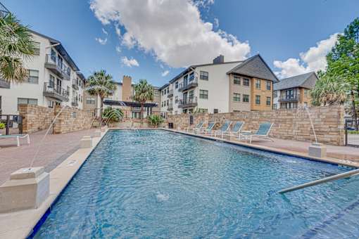 Resort style pool with lounge chairs and palms at Vue Live Oak Apartments, Dallas, 75204