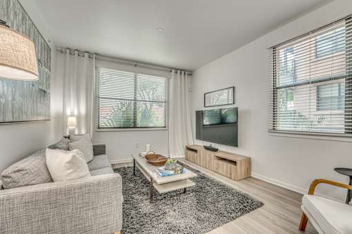 Living room with wall mounted television and blinds at Vue Live Oak Apartments, Texas, 75204