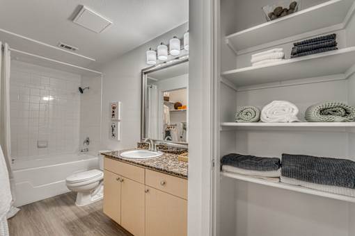 Bathroom with linen storage and granite vanity at Vue Live Oak Apartments, Dallas, TX