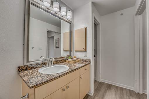 Bathroom vanity with granite countertop and mirror at Vue Live Oak Apartments, Dallas, 75204