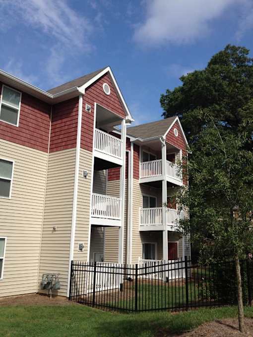 A red and beige apartment building with a black fence in front.
