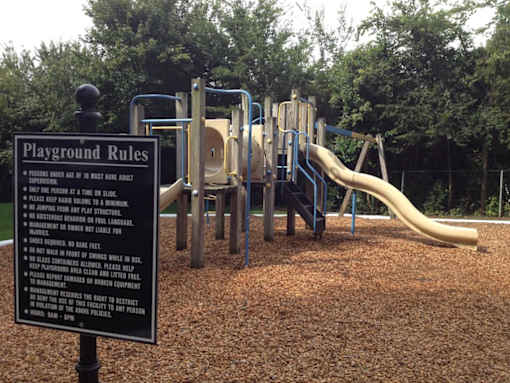 A playground with a sign that lists the rules.