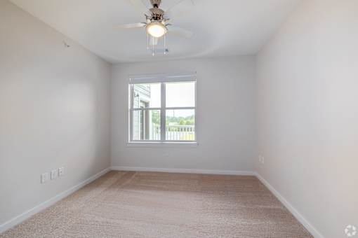 A room with a ceiling fan and carpeted floor.