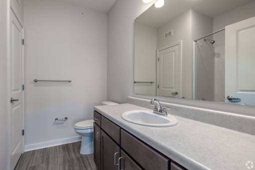 A bathroom with a toilet, sink, and mirror.