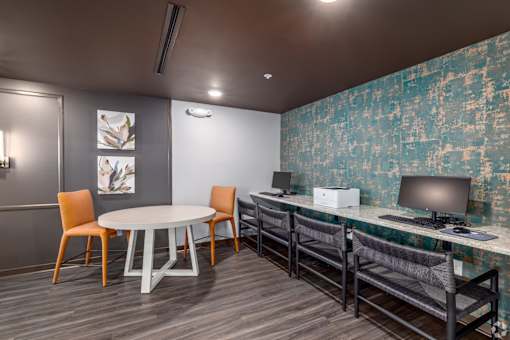 A room with a round table, chairs, and a computer desk.