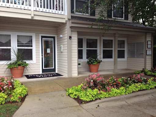 A house with a front porch and a flower bed in front.