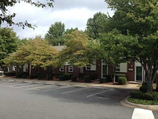 A parking lot in front of a building with trees.