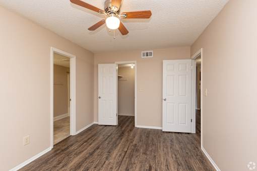 A room with a ceiling fan and wooden floors.