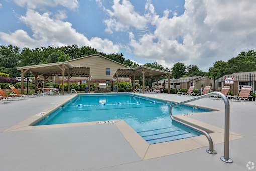 A large outdoor swimming pool with a diving board and lounge chairs.
