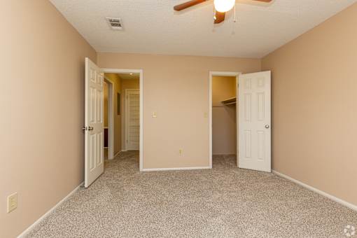 A room with a ceiling fan and two open doors.