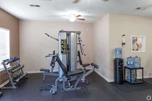 A home gym with a weight machine, a bench, and a water cooler.
