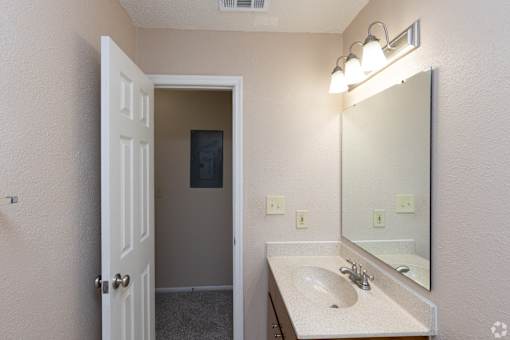 A bathroom with a sink, mirror, and light fixture.