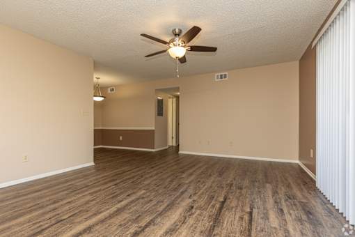 A room with a ceiling fan and wooden flooring.