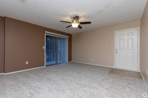 A room with a ceiling fan and a sliding glass door.