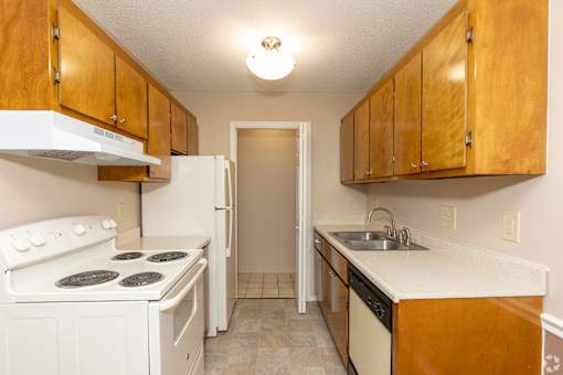 A kitchen with white appliances and wooden cabinets.