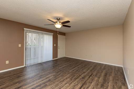 A room with a ceiling fan and sliding glass doors.