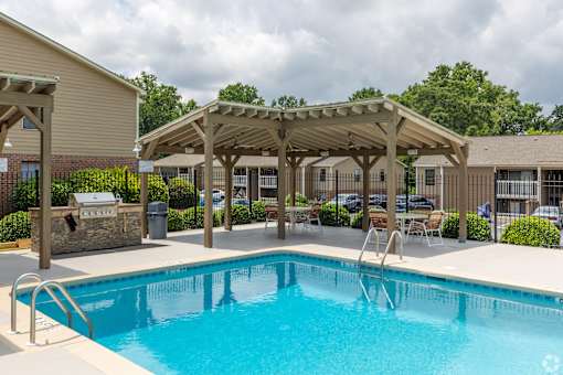 A swimming pool with a wooden pergola over it.