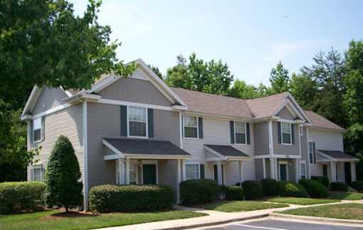 A large, two-story house with a grey and white exterior and a brown roof.