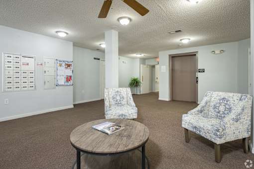 A room with a ceiling fan, two chairs, and a table.