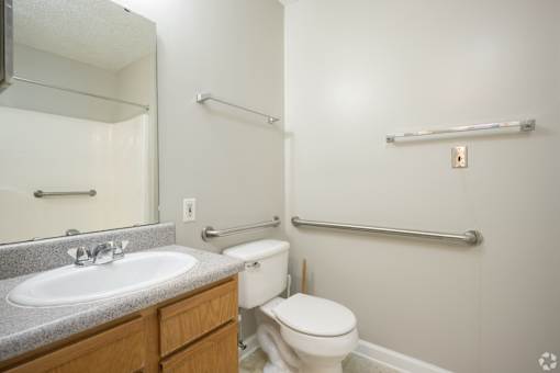 A bathroom with a toilet, sink, and towel racks.