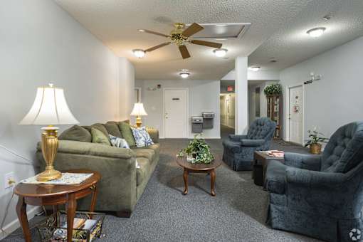 A living room with a green couch, a coffee table, and a ceiling fan.