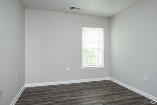A room with a window and wooden flooring.