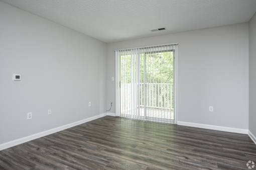 A room with wooden flooring and a sliding glass door.