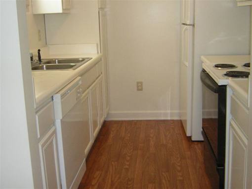 A kitchen with white cabinets and a wooden floor.