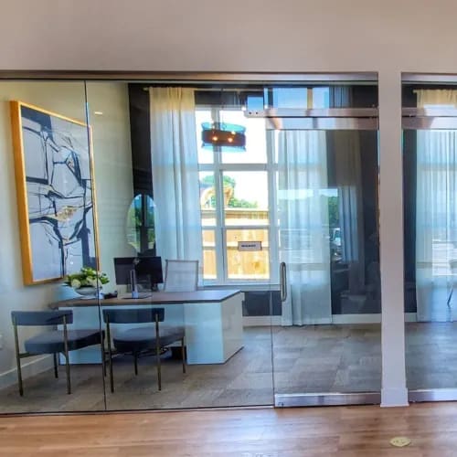 A modern room with a glass table and chairs, a TV, and a large abstract painting on the wall.