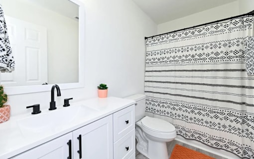 A white bathroom with a black and white shower curtain.