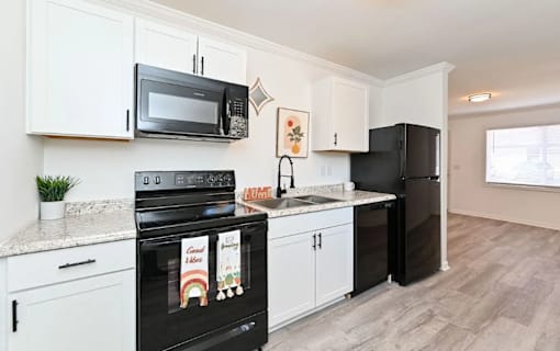 A kitchen with black appliances and white cabinets.