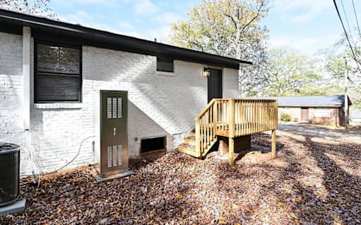 A white house with a wooden deck in front.
