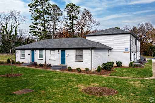 A white house with a grey roof and a blue door.
