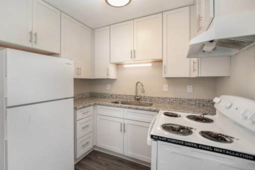 A kitchen with white appliances and cabinets is under construction.