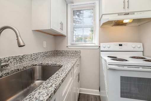 A white stove is in a kitchen with granite countertops.